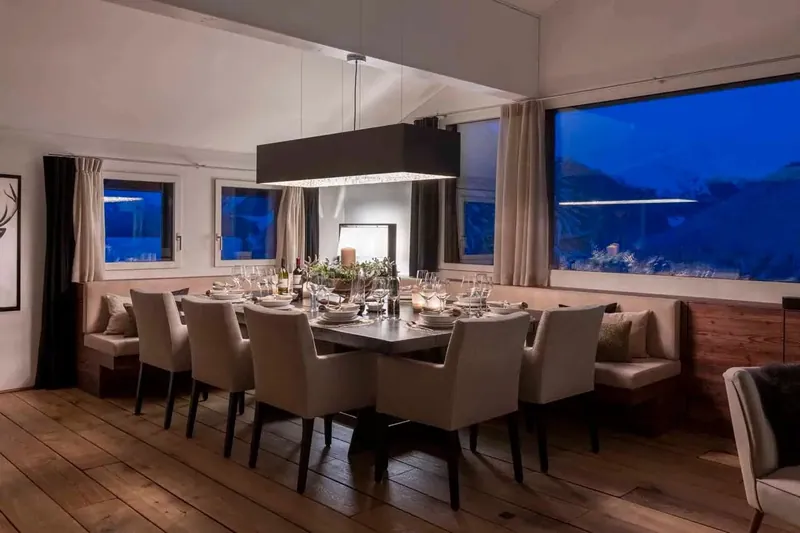 The dining table at Chalet Kyla with panoramic windows at dusk