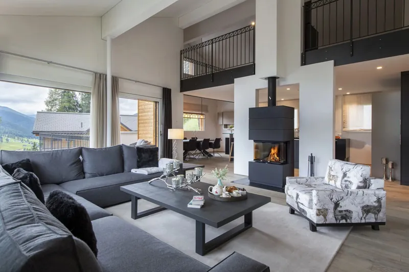 Open-plan living room with a suspended fireplace and mountain windows at Chalet Kyla, Davos